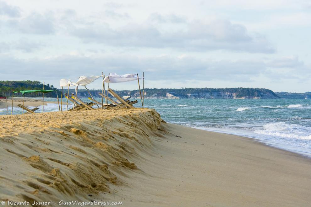 Imagem de espreguiçadeira de madeira nas areias da Praia da Barra Velha.